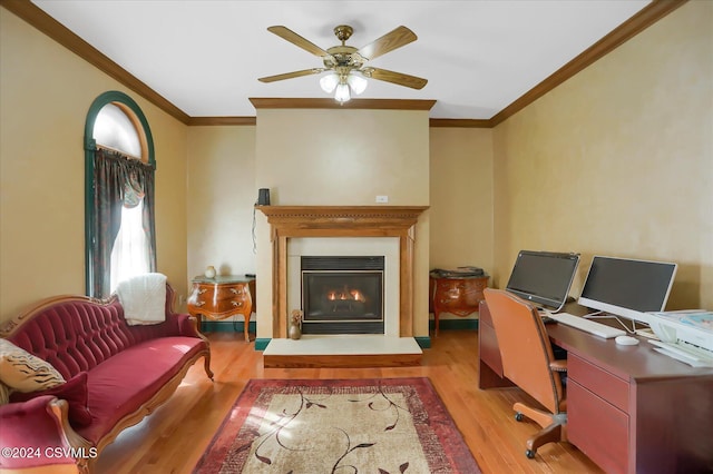 office space featuring a glass covered fireplace, ceiling fan, ornamental molding, and wood finished floors