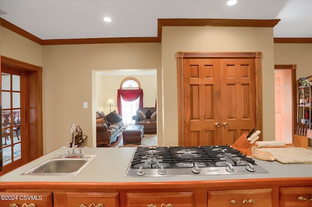 kitchen featuring light countertops, stainless steel gas cooktop, a sink, and crown molding