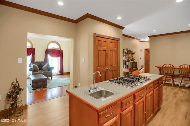 kitchen featuring stainless steel gas cooktop, light wood finished floors, a sink, and black microwave