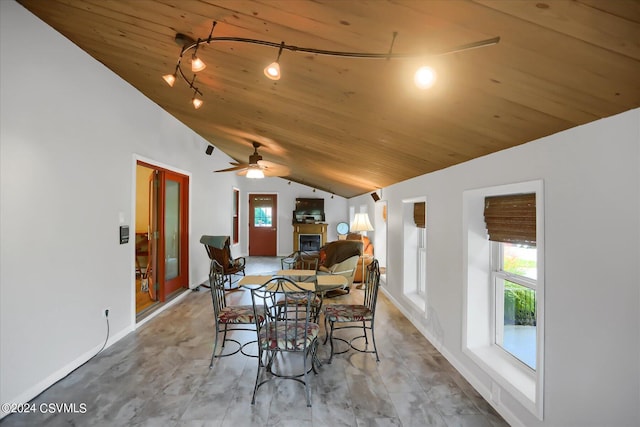 dining area featuring wood ceiling, a healthy amount of sunlight, a glass covered fireplace, and lofted ceiling