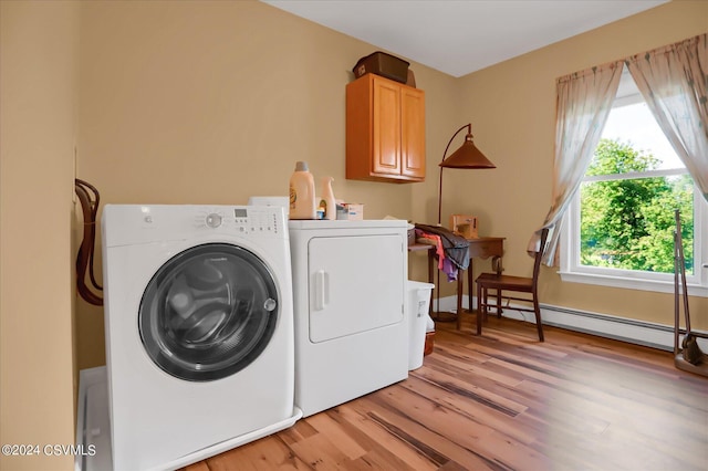 washroom featuring cabinet space, washing machine and clothes dryer, a baseboard heating unit, and light wood-style floors