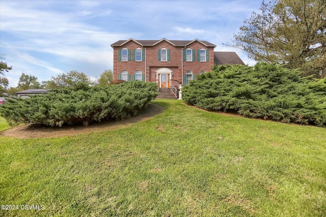 colonial home with a front yard and brick siding