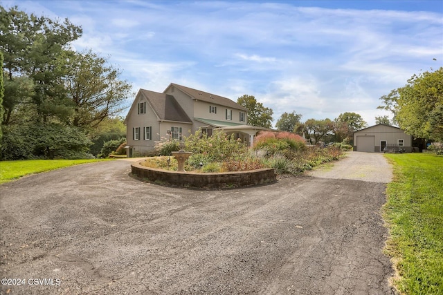 view of front facade featuring an outbuilding, driveway, and a detached garage