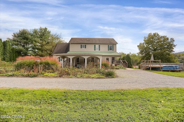 view of front facade featuring gravel driveway, a front yard, and covered porch