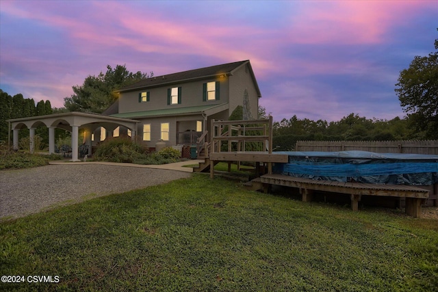 rear view of property featuring a yard, a deck, fence, and a fenced in pool