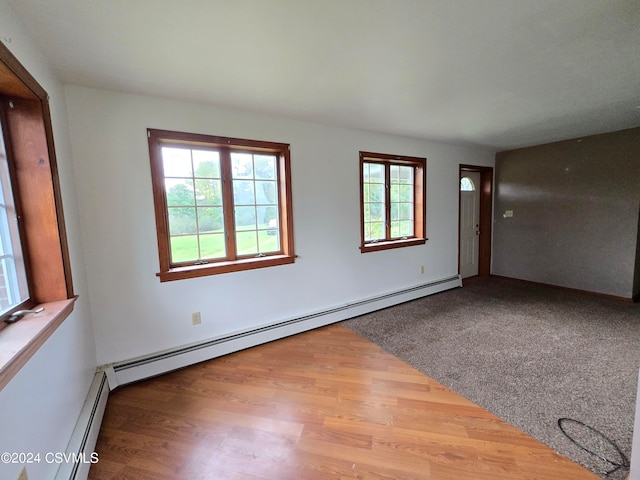 empty room featuring baseboard heating and wood-type flooring