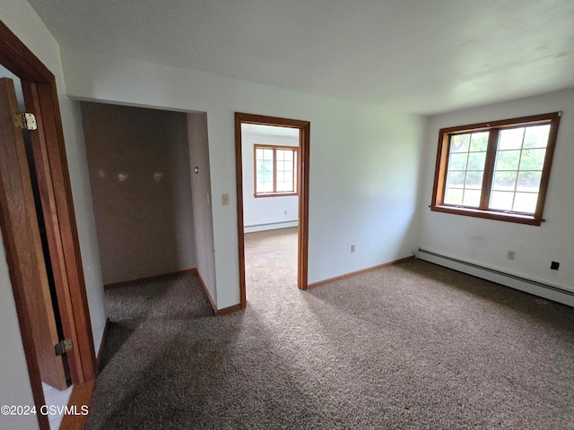 unfurnished room with a baseboard radiator, dark carpet, and plenty of natural light