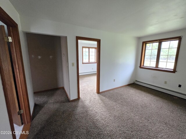 spare room featuring baseboards, carpet, and a baseboard heating unit