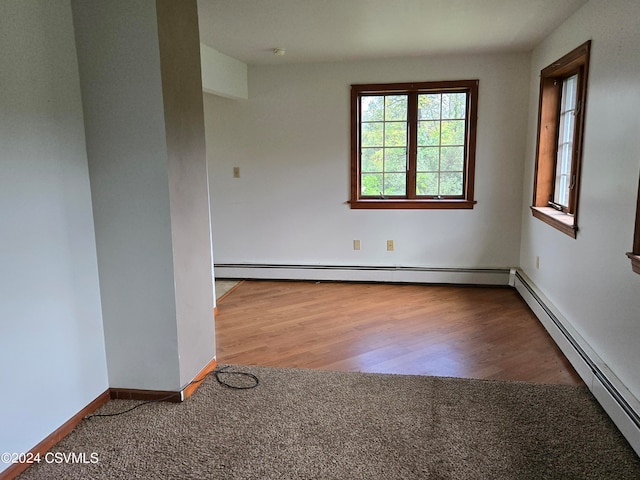 unfurnished room with a baseboard heating unit and light hardwood / wood-style floors