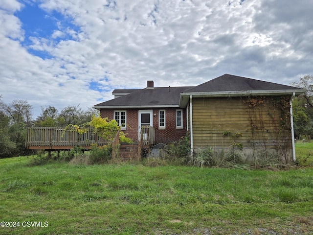 rear view of house featuring brick siding, a chimney, and a deck