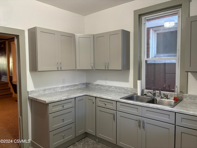 kitchen featuring gray cabinets, dark colored carpet, and sink