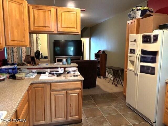 kitchen featuring white fridge with ice dispenser and dark tile patterned flooring