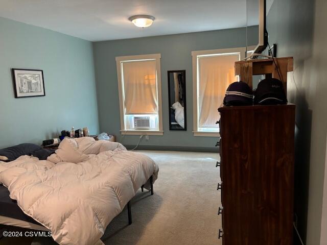 bedroom with cooling unit and light colored carpet