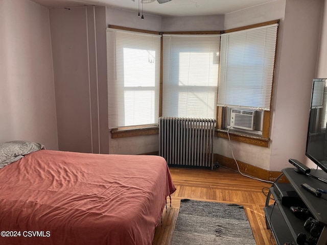 bedroom featuring hardwood / wood-style flooring, cooling unit, and radiator