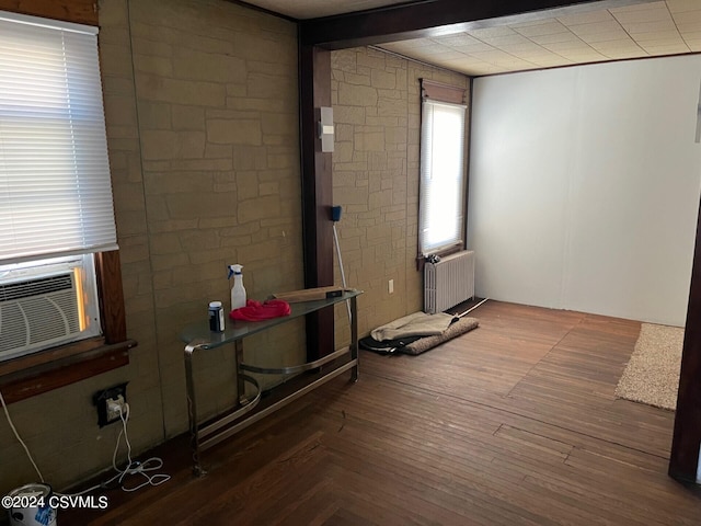 interior space with cooling unit, beamed ceiling, dark hardwood / wood-style floors, and radiator heating unit