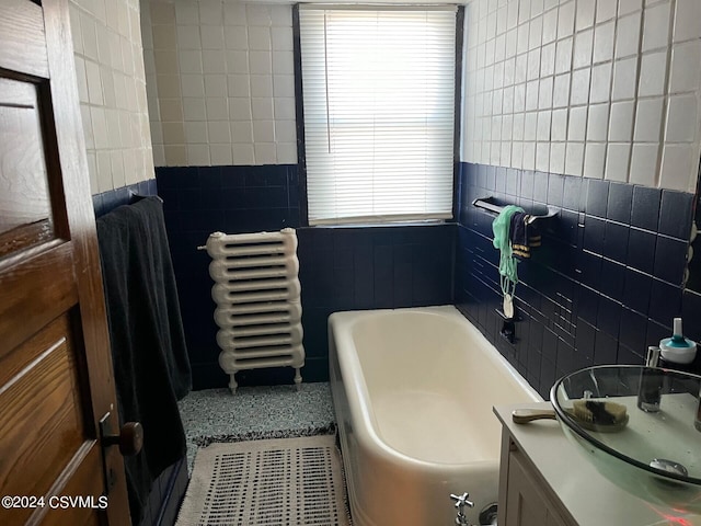 bathroom featuring vanity, tile walls, and a tub