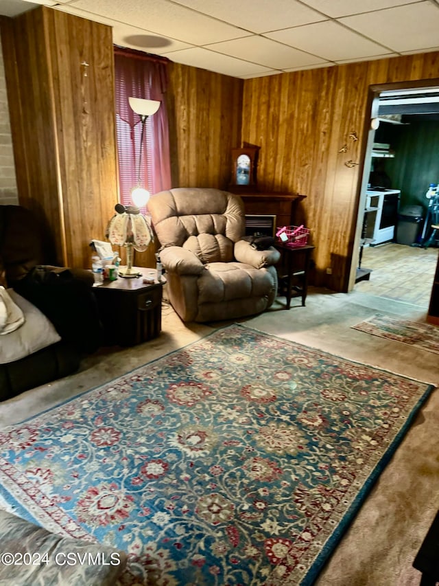 living room with a drop ceiling and wooden walls