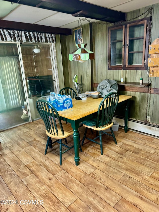 dining room with light wood-type flooring and wood walls