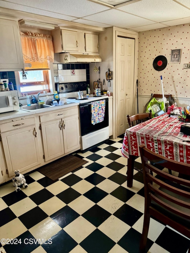 kitchen featuring decorative backsplash, a drop ceiling, white appliances, sink, and cream cabinetry