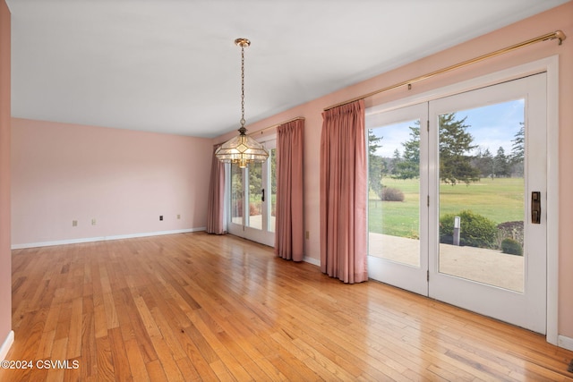 unfurnished dining area featuring light wood-type flooring, a healthy amount of sunlight, and a notable chandelier