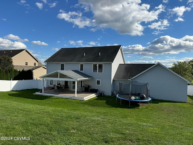 back of house featuring a patio, a trampoline, and a lawn