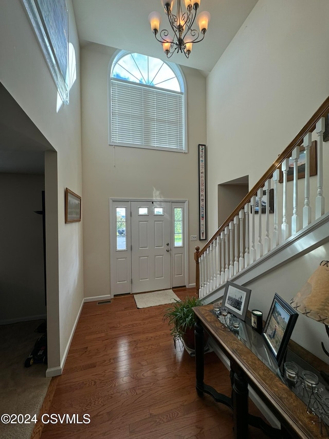 foyer entrance with a high ceiling, hardwood / wood-style floors, and an inviting chandelier