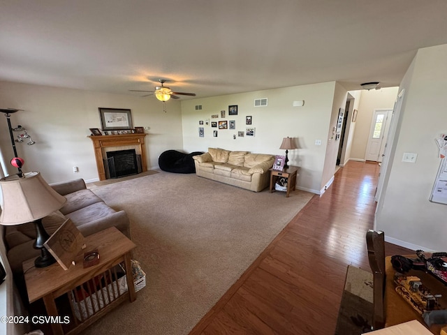 living room featuring ceiling fan, hardwood / wood-style flooring, and a fireplace