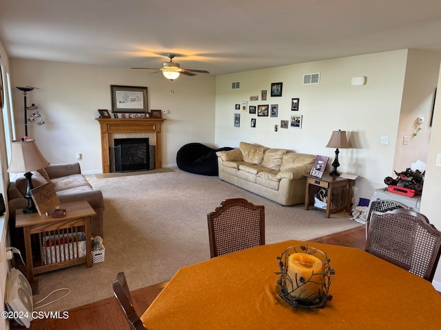 living room featuring ceiling fan, carpet, and a tiled fireplace