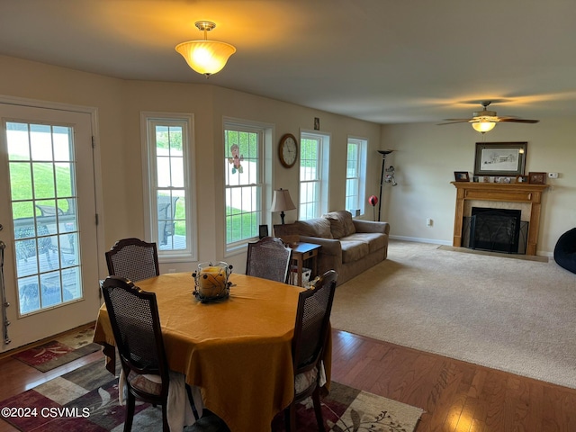 dining space with ceiling fan, hardwood / wood-style flooring, and a tile fireplace