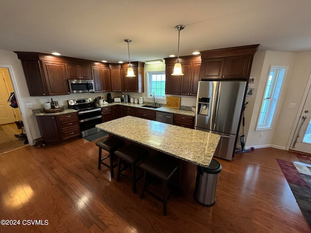 kitchen featuring a center island, dark hardwood / wood-style floors, sink, pendant lighting, and appliances with stainless steel finishes