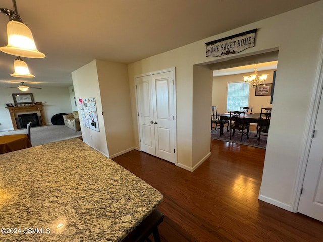 interior space featuring ceiling fan with notable chandelier, decorative light fixtures, and dark hardwood / wood-style flooring