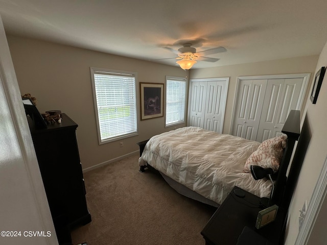 bedroom with ceiling fan, multiple closets, and carpet flooring