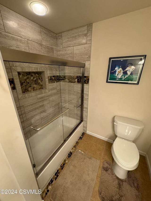 bathroom featuring bath / shower combo with glass door, tile patterned flooring, and toilet