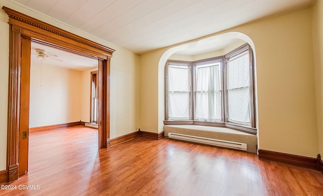 spare room featuring hardwood / wood-style floors, a baseboard heating unit, and ceiling fan