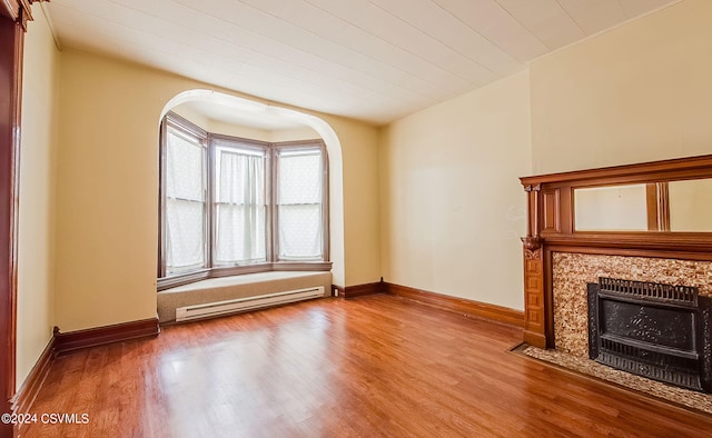 unfurnished living room with wood-type flooring and a baseboard radiator