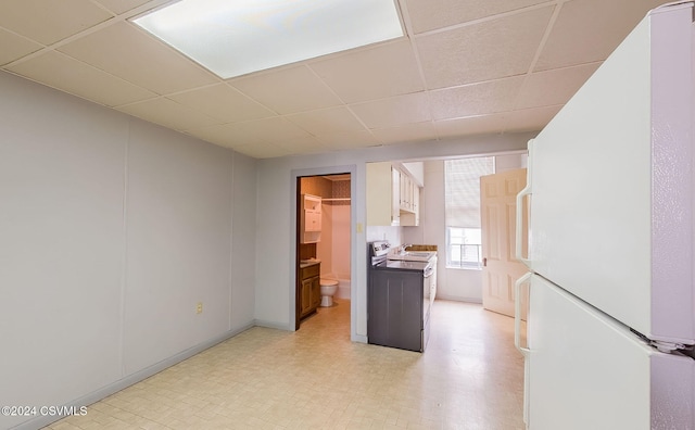 kitchen featuring white cabinetry, stainless steel electric stove, a paneled ceiling, and white refrigerator