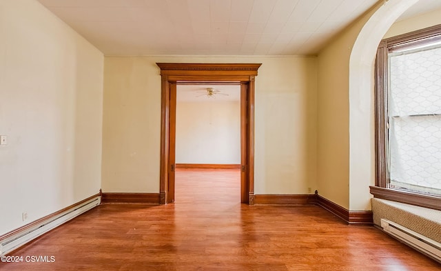 spare room with baseboard heating and light hardwood / wood-style flooring