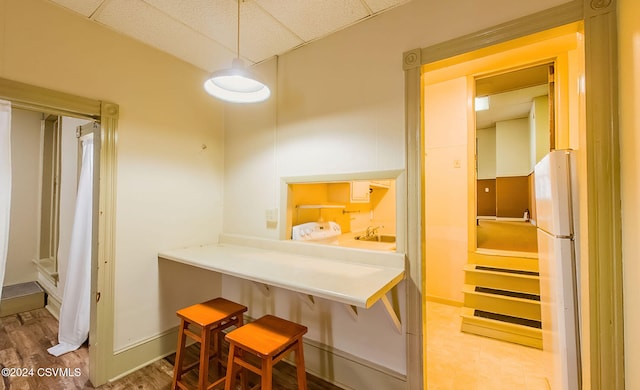 kitchen with white fridge, a paneled ceiling, sink, and hardwood / wood-style floors