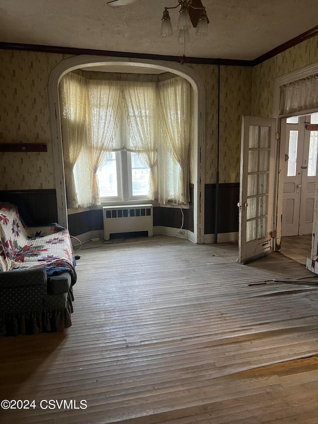 unfurnished room featuring crown molding, radiator heating unit, hardwood / wood-style flooring, and ceiling fan