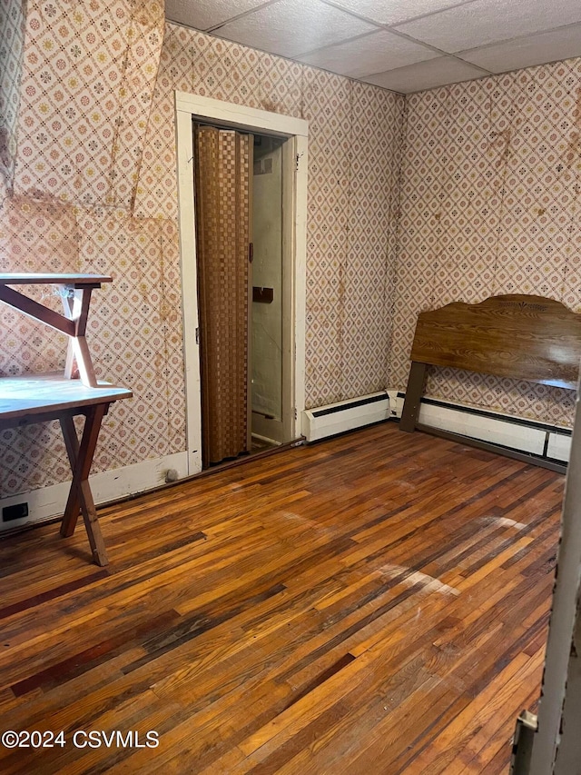 interior space featuring a paneled ceiling, dark wood-type flooring, and a baseboard radiator