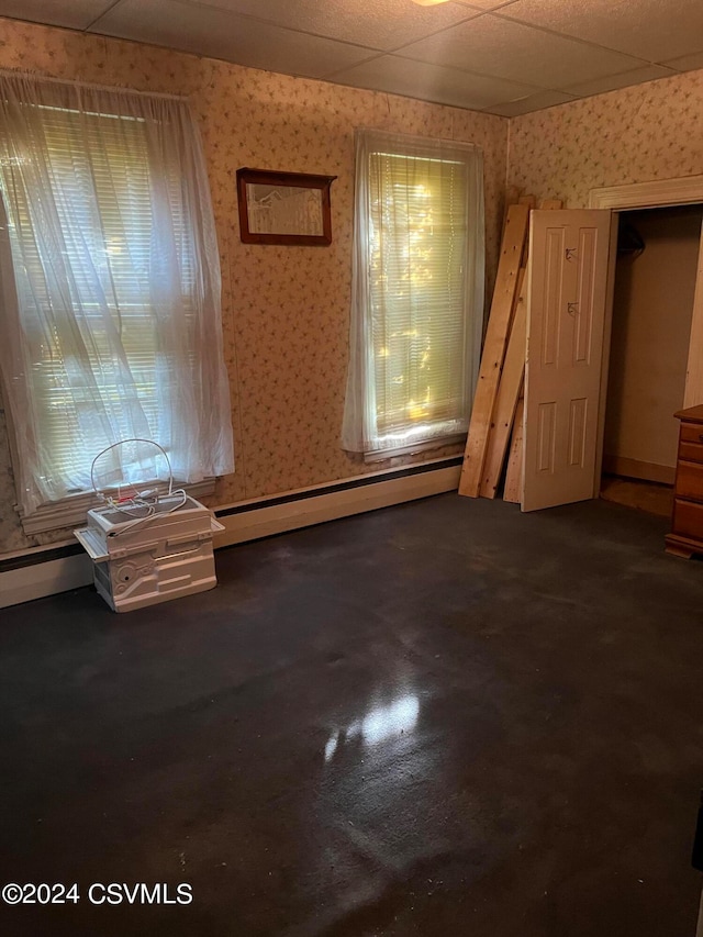 empty room featuring a drop ceiling and baseboard heating