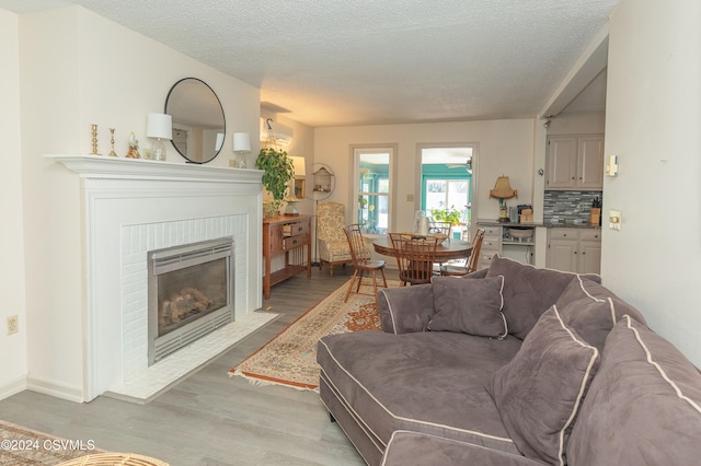 living room with a textured ceiling, light wood-type flooring, and a fireplace