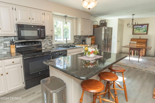 kitchen featuring decorative backsplash, a kitchen island, white cabinetry, black appliances, and sink