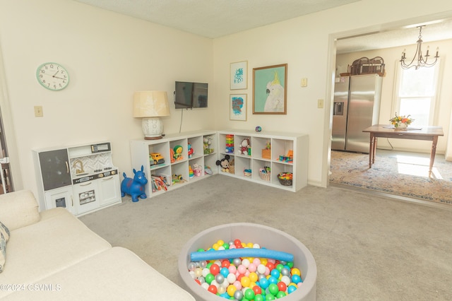 rec room featuring an inviting chandelier, carpet floors, and a textured ceiling