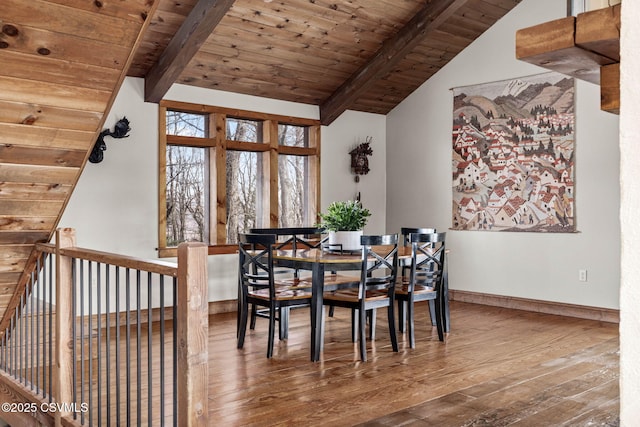 dining space with lofted ceiling with beams, hardwood / wood-style flooring, wood ceiling, and baseboards