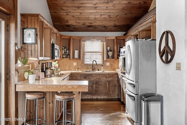 kitchen featuring appliances with stainless steel finishes, wood ceiling, light countertops, and a peninsula