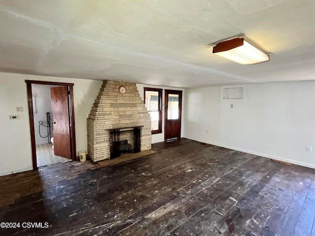 unfurnished living room with a stone fireplace and dark hardwood / wood-style flooring