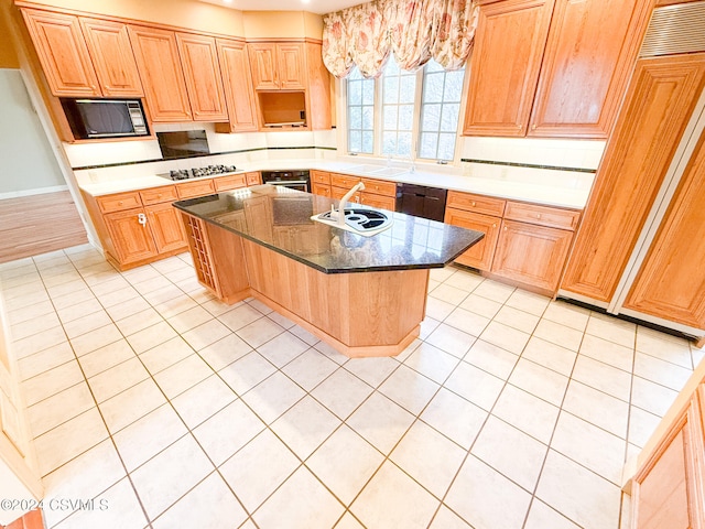 kitchen with a kitchen island with sink, black appliances, sink, and light tile patterned flooring