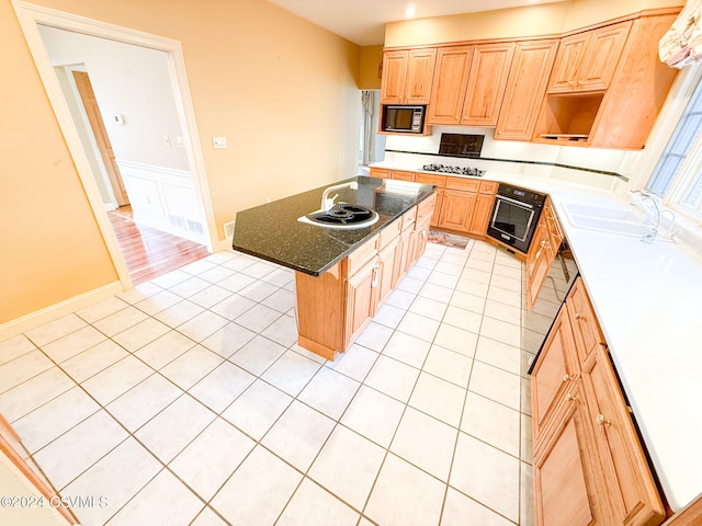 kitchen with black appliances, a breakfast bar area, sink, and a center island