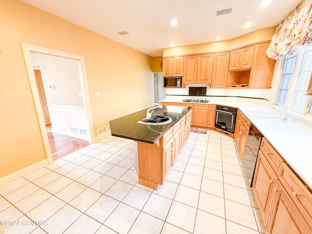 kitchen with light tile patterned floors, sink, black appliances, and a kitchen island